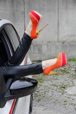 Bir kadın bacaklarını bir araba yüksek topuklu pencereden dışarı uzanır