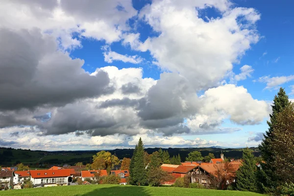 Duże białe chmury w błękitne niebo nad wioską w Bawarii. Silne chmury na niebie — Zdjęcie stockowe