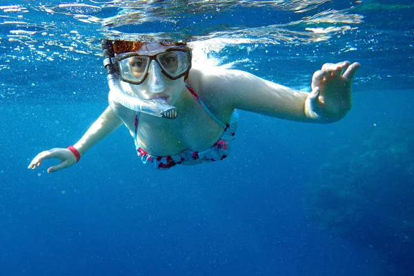 A woman snorkels in the sea. Snorkeling woman in the Red Sea. A woman with diving goggles underwater. — Stock Photo, Image