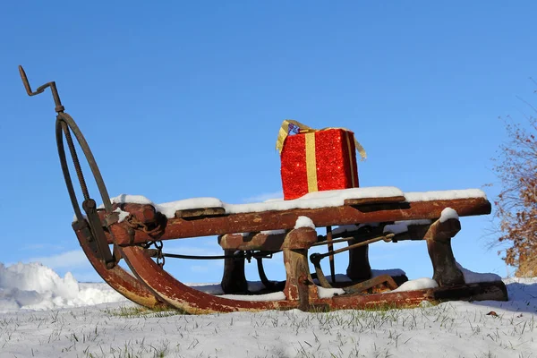 Een kerst slee in de sneeuw. Een slee van de kerstman met een rode cadeau — Stockfoto