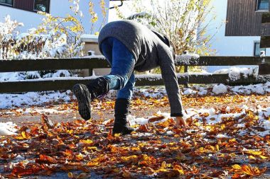 Risk of slipping in autumn and winter. A woman slipped on wet, smooth leaves. clipart