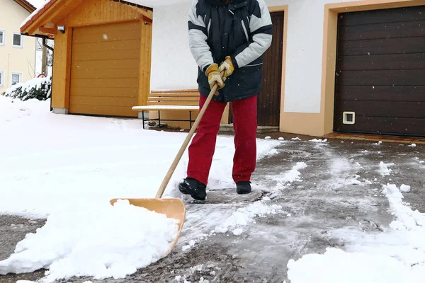 Um homem pás neve na frente das garagens — Fotografia de Stock