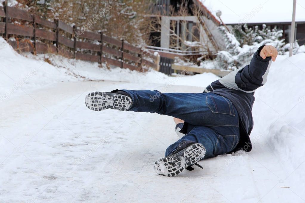 Accident danger in winter. A man has slipped and has fallen down