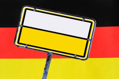 Alman bayrağının önünde boş sarı bir Alman sokak tabelası