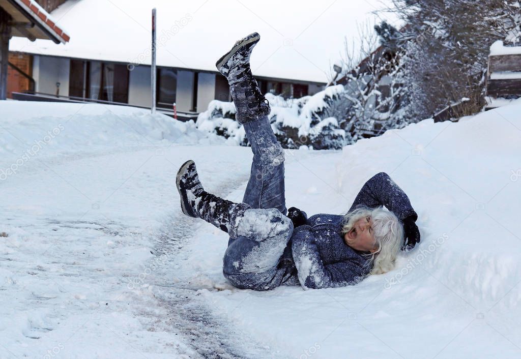 A woman slipped on the winter road, fell down and hurt herself. Fall on slippery roads