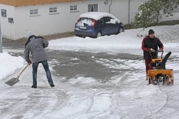 Two men are clearing snow from the road in winter. Snow clearing with shovel and snow blower