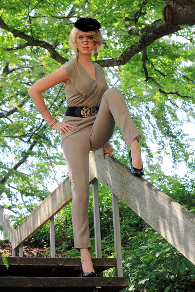 A young tall slender blonde woman in a pantsuit with a fancy hat