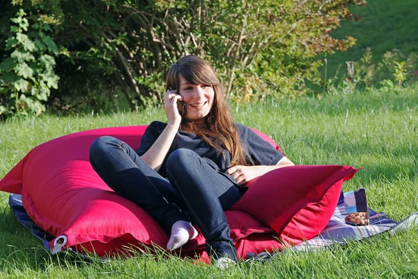 A young woman on the phone in the garden with her smartphone
