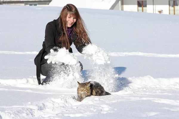 雪の中で冬に彼女の猫と遊ぶ若い女性 — ストック写真