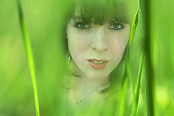 Artistic work - The face of a young woman between blades of grass