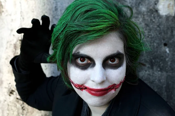 A young woman in Joker\'s mask. A young woman with a make-up clown face