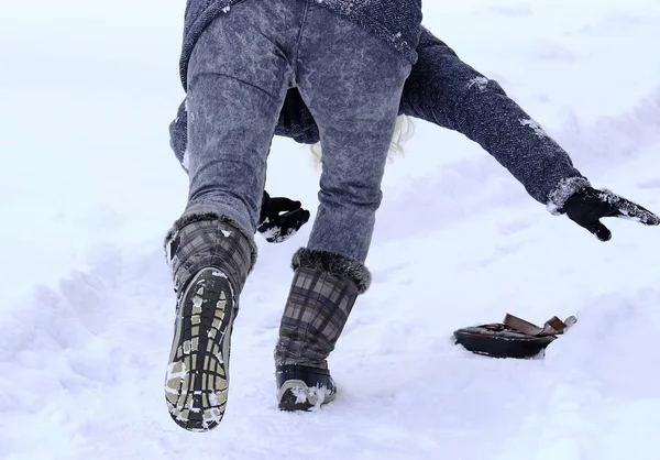 雪に覆われた歩道に女性が滑り込む — ストック写真