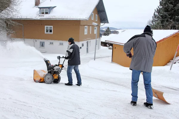 两个人用吹雪机和铲子清扫道路和人行道 — 图库照片