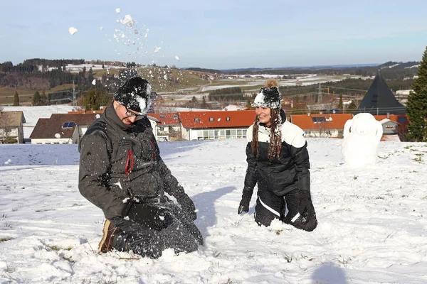 若い夫婦は冬に雪合戦をする 雪の中で女と男は楽しむ — ストック写真