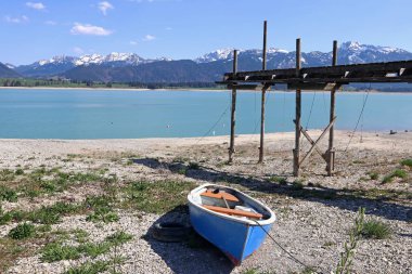 Bavyera 'da bir gölde mavi bir tekne. Allgaeu 'de suyu az olan Forggensee.