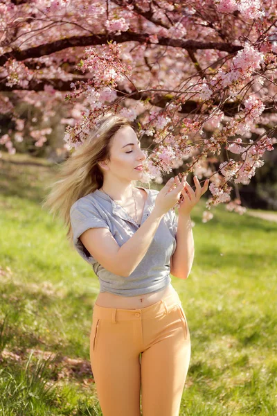 Krásná šťastná mladá žena v zahradě kvetoucí na jaře — Stock fotografie