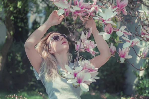 Mulher jovem saudável bonita com flores de magnólia. Imagem tonificada — Fotografia de Stock