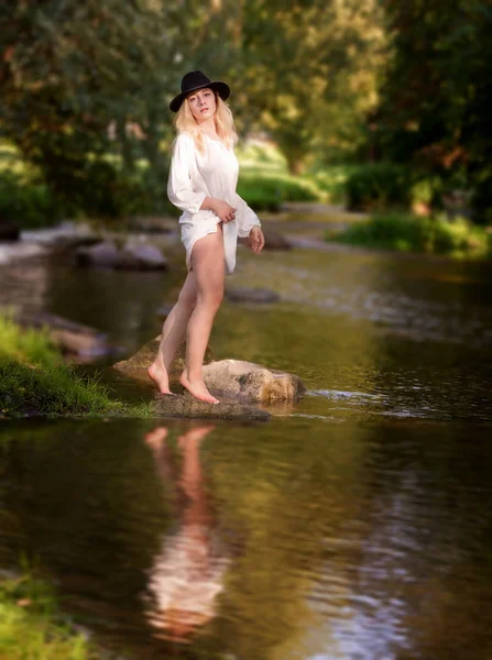 Mladá žena v bílých šatech uprostřed potoka.. — Stock fotografie