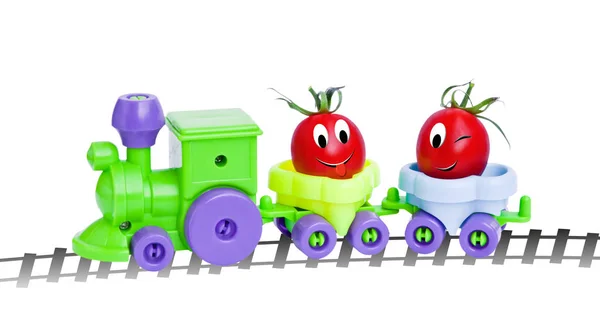 Pomodori ciliegia maturi in un treno giocattolo. Personaggi divertenti dall'idea originale del concetto . — Foto Stock