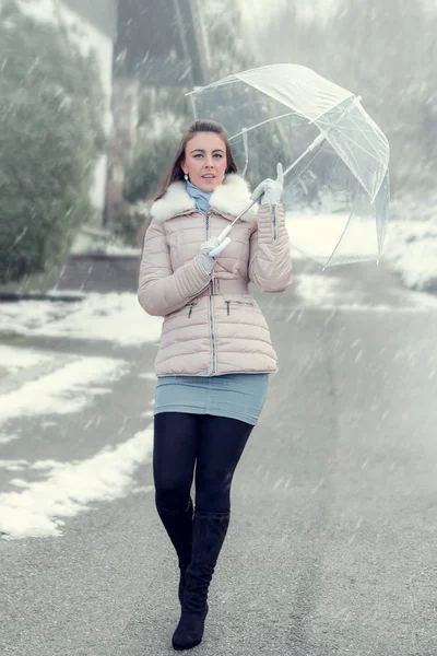 Young woman under an umbrella in a snowfall. — Stock Photo, Image