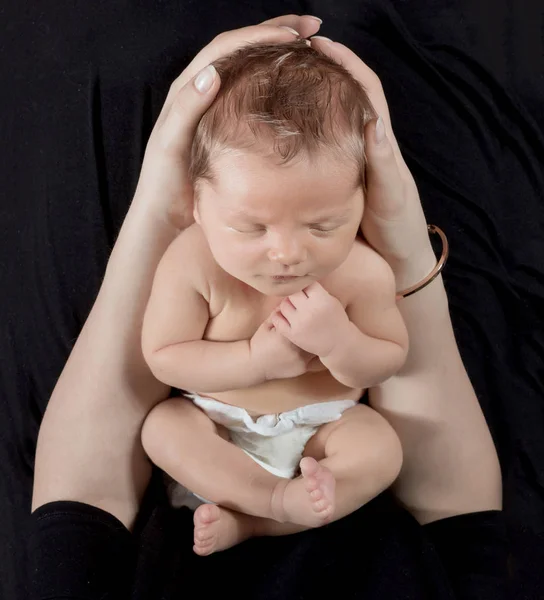 Pasgeboren baby in de armen van een moeder. — Stockfoto