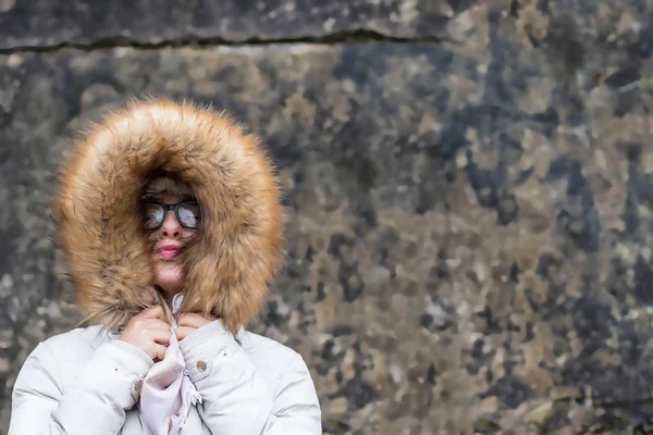 Portrait of a young woman in a fur jacket against a wall grunge — Stock Photo, Image