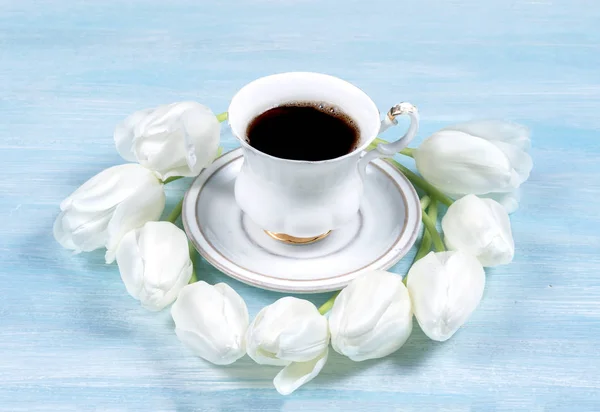 Kopje koffie op een tafel met witte tulpen. Bovenaanzicht. — Stockfoto