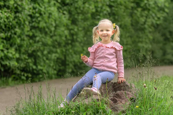 Klein meisje zittend op de steen en lacht — Stockfoto