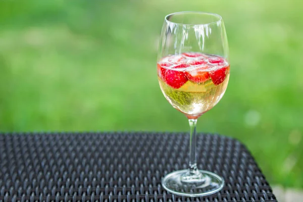 Glass of champagne with strawberries on a table outdoors. Rossini cocktail — Stock Photo, Image