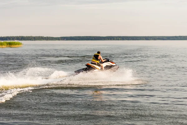 Un homme conduisant un jet ski, rabougrissant et faisant des gouttes d'eau — Photo