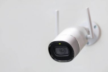 Beyaz güvenlik kamerası. CCTV duvara monte. Wifi kablosuz antenler etkin. Big brother kavramı izlerken