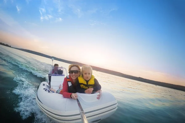 Couple heureux avec fille chevauchant bateau sur le lac ou la rivière au coucher du soleil. Associez-vous à un enfant faisant du selfie pendant l'activité aquatique. Happy concept de loisirs et d'aventure en famille. Beau fond de voyage — Photo