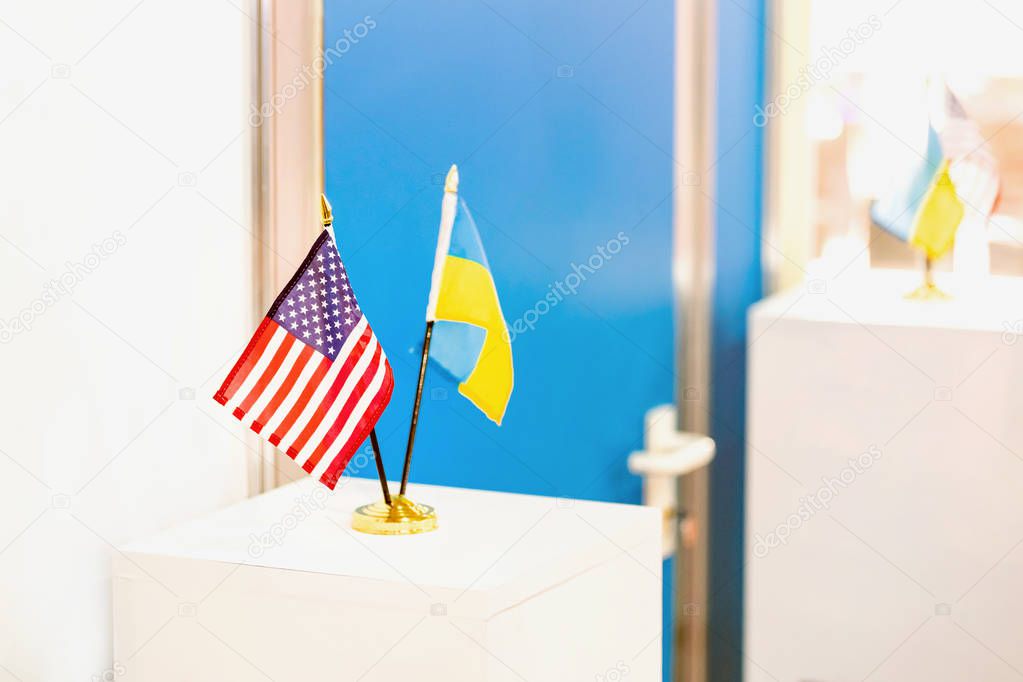 Ukrainian and USA flags stand together. Closed door on the background. Government negotiations. Partnership and cooperation concept