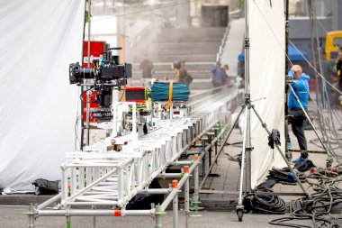 Big professional camera on rails. Outdoors movie set. Cinema production scene at city street.  Candid real filmmaking concept clipart