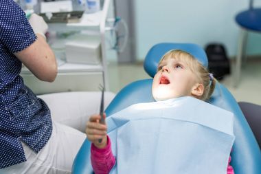 Bebek kız ziyaret stomatology Kliniği. Çocuklar diş muayenesi yapmak dişçi. Çocuk bir cımbız tutan yordamda dahil. Diş Bakımı oyunu şeklinde. Kolay çocuk diş hekimi kavramı