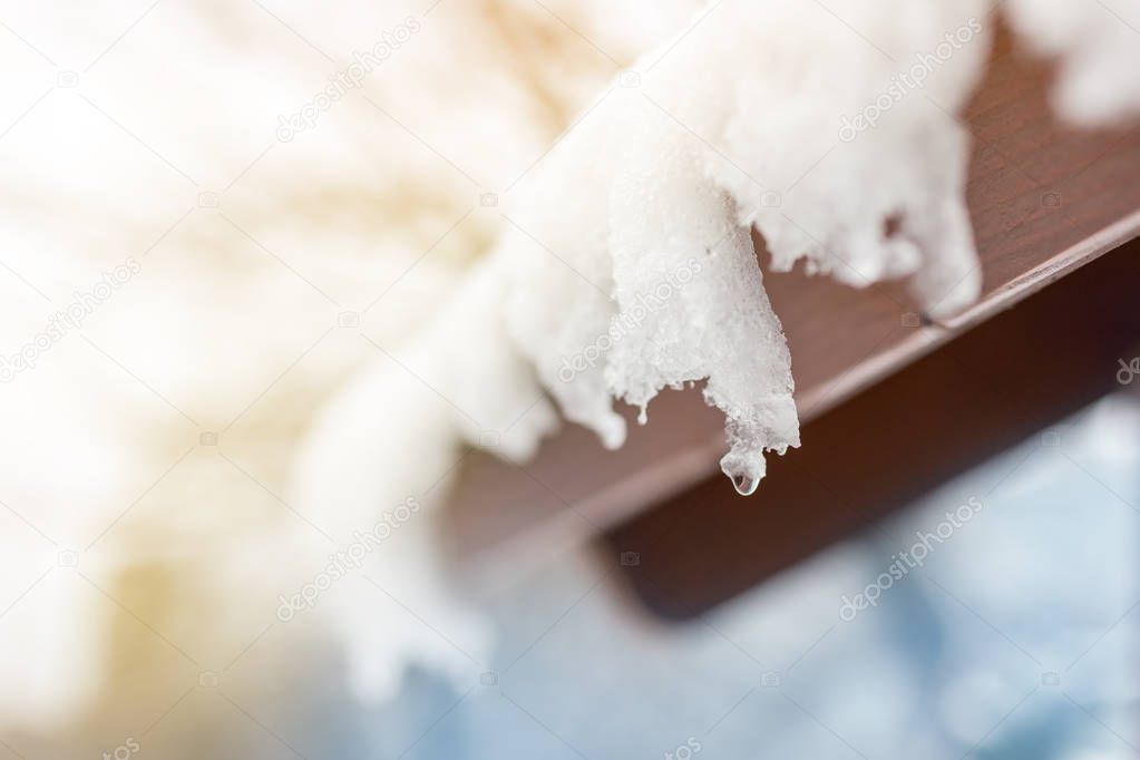 Close-up of melting snow icicles on roof. Falling water drops. Beginning of spring. Meeting cold and heat concept. Fresh spring nature background