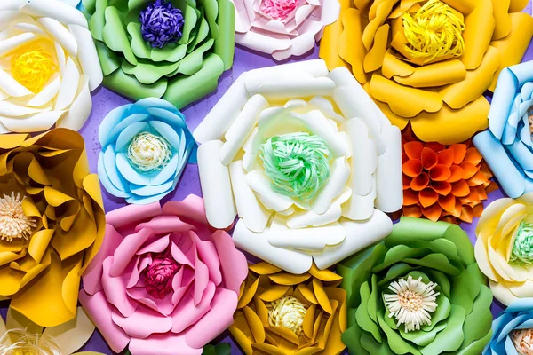 Colorful paper flowers on wall. Handmade artificial floral decoration.  Spring abstract beautiful background and texture