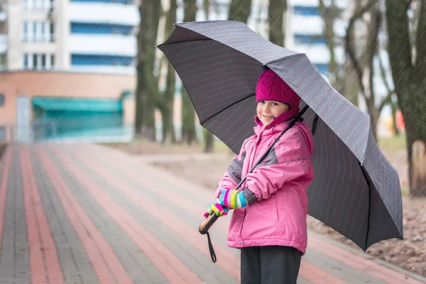 Mała dziewczynka chodzenie pod parasolem w parku — Zdjęcie stockowe