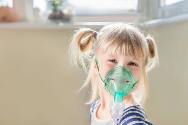 Um miúdo sorridente feliz a usar máscara de nebulizador. Terapia inalatória cura de resfriado no peito e tosse. Conceito de cuidados de saúde e prevenção de doenças — Fotografia de Stock