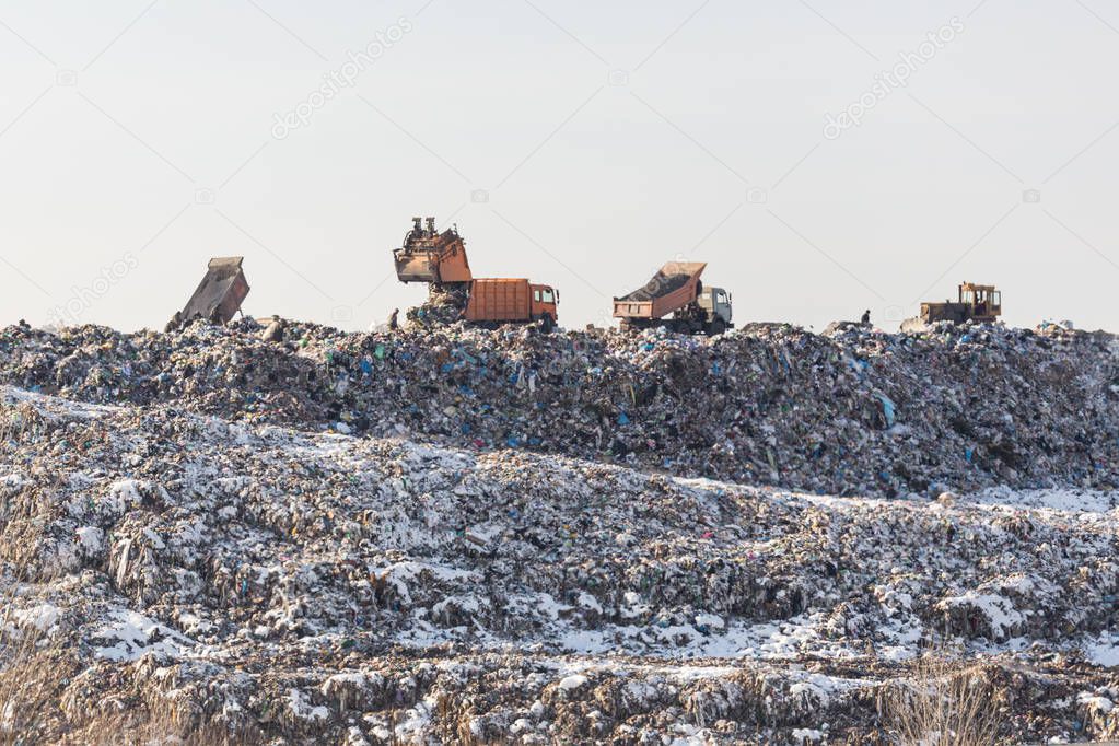 Dump trucks unloading garbage over vast landfill.  Environmental pollution. Outdated method of wasate disposal. Survival of times past