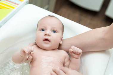 İlk banyoda sevimli sevimli bebek çocuk. Anne bebek rahat sıcaklık su ile yıkar. Yeni doğan hijyen ve sağlık kavramı