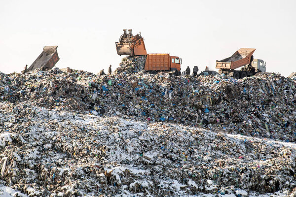 Dump trucks unloading waste over huge sanitary fill.  Environmental pollution. Out of date technology