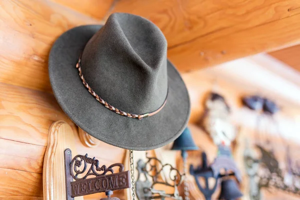 Sombrero clásico de fieltro vintage colgado en la pared. Entrada de casa de madera rústica. Placa de bienvenida cerca de la puerta. Estilo de vida rural — Foto de Stock