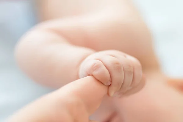 Новонароджена дитина тримає батьківський палець. М'який фокус, розмитий фон. щасливе батьківство та концепція дитячої невинності — стокове фото
