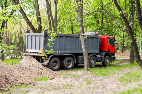 Gran camión volquete cerca del montón de tierra. Reconstrucción del parque urbano con maquinaria pesada — Foto de Stock