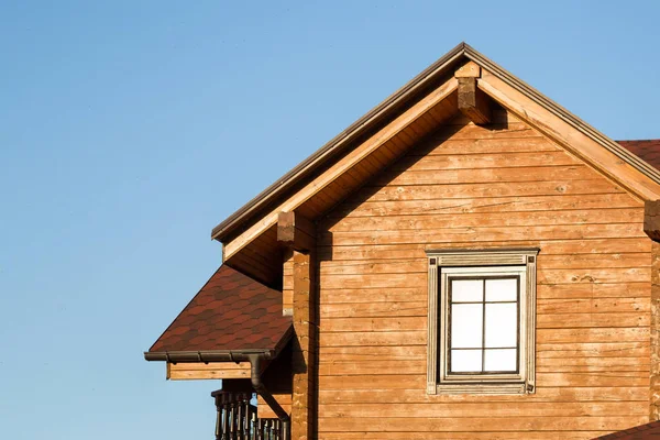 Parte della moderna casa di campagna in legno con cielo blu sullo sfondo. Tetto di eco edificio residenziale vicino foresta. Edificio e architettura di chalet rustico — Foto Stock