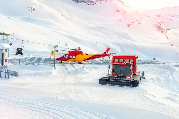Estação de resgate de vida de esqui de montanha com máquinas pesadas. Helicóptero, snowcat e snowmobile pronto para salvar o turista em acidente na estância de esqui alpino austríaca. Alpes natureza landsape fundo — Fotografia de Stock