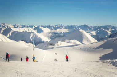 Güneşli bir günde dağ tepesindeki dağ tepesindeki kayak kaldırma halat istasyonu. İnsanlar kayak ve snowboard yapmaktan zevk alıyor. Yokuş aşağı geniş panoramik manzara