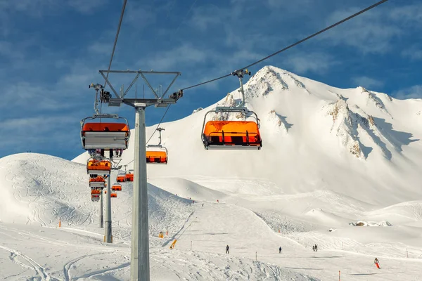 Remontées mécaniques sur les collines station d'hiver de montagne alpine par une journée ensoleillée. Téléski télésiège téléphérique avec les gens aiment le ski et le snowboard.Bannière panoramique large vue sur les pistes de descente — Photo
