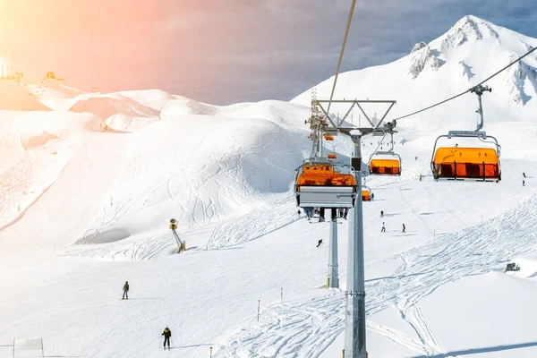 Remontées mécaniques sur les collines station d'hiver de montagne alpine par une journée ensoleillée. Téléski télésiège téléphérique avec les gens aiment le ski et le snowboard.Bannière panoramique large vue sur les pistes de descente — Photo